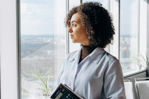 Mulher adulta olhando pela janela com expressão confiante e serena, representando a reconstrução da autoconfiança após desafios profissionais.